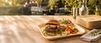 Burger mit gegrilltem Gemüse auf einem quadratischen Palmblatt-Teller im Garten